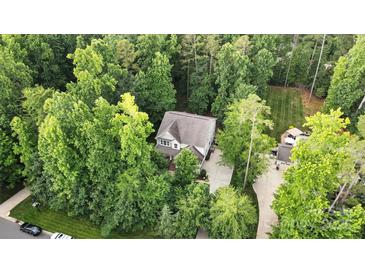 An aerial view of a house surrounded by lush green trees, a large driveway, and a well-manicured lawn at 8214 Aspen Ct, Mint Hill, NC 28227