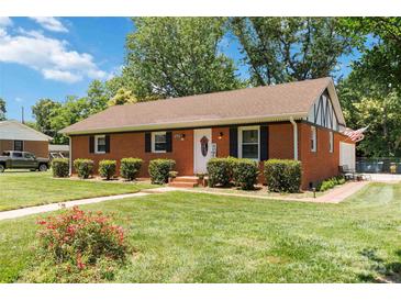 Charming brick home with manicured lawn, lush shrubbery, and welcoming front entrance at 1219 Flowe Dr, Matthews, NC 28104