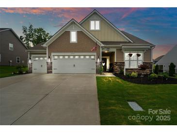 Inviting home with a two-car garage, stone accents, manicured lawn, and charming curb appeal at dusk at 17733 Burnt Hickory Dr, Charlotte, NC 28278