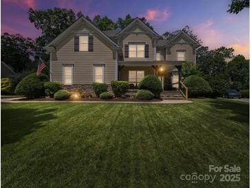 Charming two-story home with manicured lawn and stone accents, illuminated by warm lighting at dusk at 1808 Mill Chase Ln, Waxhaw, NC 28173