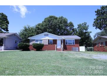 Charming brick home with a well-maintained lawn and mature trees on a sunny day at 1926 Eastway Dr, Charlotte, NC 28205