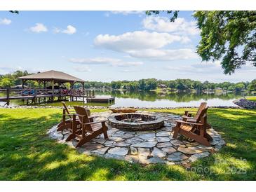 Inviting lakefront fire pit with stone surround and Adirondack chairs perfect for relaxing by the water at 4485 River Oaks Rd, Lake Wylie, SC 29710