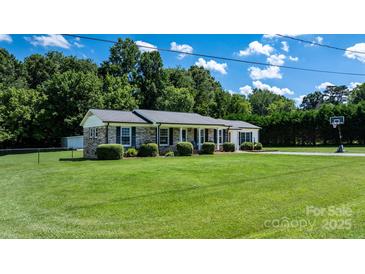 Charming brick home with a well-manicured lawn, mature trees, and a long driveway, set under a sunny sky at 50 Isenhour Park Rd, Taylorsville, NC 28681