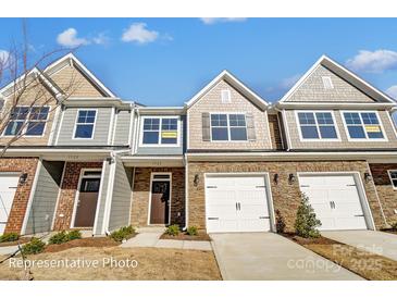 Charming townhomes with stone accents, attached garages, and well-manicured lawns offer modern living at 6274 Tea Olive Dr # 237, Harrisburg, NC 28075
