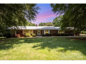 Charming one-story brick home features a lush green lawn and mature trees in a serene setting at 114 Huffstetler Rd, Gastonia, NC 28056