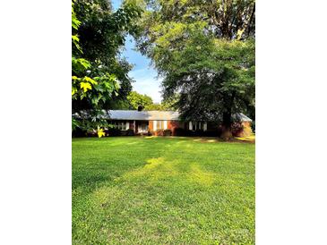 Charming brick home nestled on a lush, expansive green lawn with mature trees at 114 Huffstetler Rd, Gastonia, NC 28056