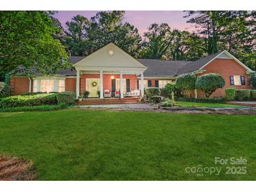 Beautiful brick home featuring a large front yard and covered porch with yellow front door at 307 Dogwood Dr, Mount Holly, NC 28120