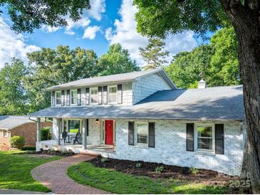 Charming two-story home with a welcoming front porch, painted brick, a red door, and beautifully landscaped yard at 310 25Th Nw Ave, Hickory, NC 28601