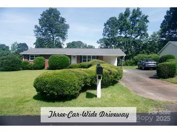 Charming one-story brick home with a well-maintained front lawn and an inviting three-car-wide driveway at 4429 Dawnwood Dr, Gastonia, NC 28056