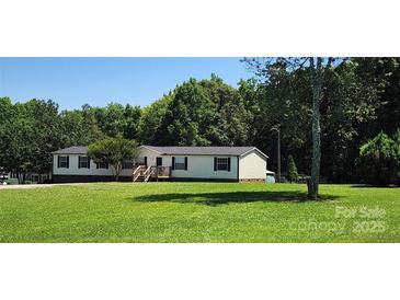 Single story home with front porch nestled amongst mature trees on a large lot at 4688 Taxahaw Rd, Lancaster, SC 29720