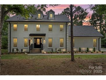 Beautiful two story white brick home with black trim, a dark roof, and manicured lawn at 9830 Spring Harvest Dr, Mint Hill, NC 28227