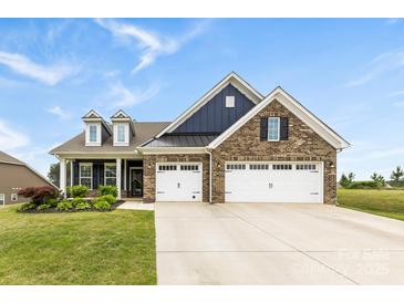Charming brick home featuring a three-car garage, dormers, and a manicured lawn at 1300 Dali Blvd, Mount Holly, NC 28120