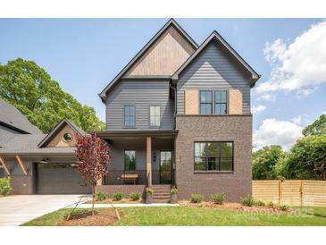 Charming two-story home featuring a brick facade, gray siding, and a covered front porch at 1830 Commodore St, Charlotte, NC 28205