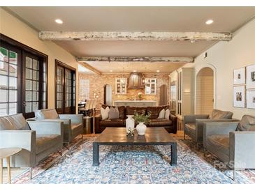 Open-concept living room featuring exposed wood beams, hardwood floors, brick walls and elegant furnishings at 4023 Alexandra Alley Dr, Charlotte, NC 28210