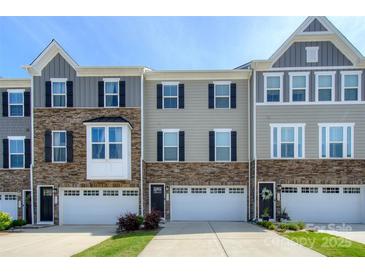 Charming townhouse exterior featuring stone accents, neutral siding, and attached garages under a clear blue sky at 411 Lahinch Dr, Tega Cay, SC 29708