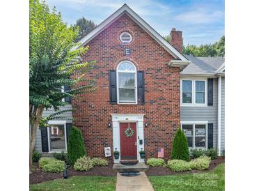 Charming brick townhouse featuring a red front door, black shutters, and manicured landscaping at 1735 Robinwood Rd, Gastonia, NC 28054