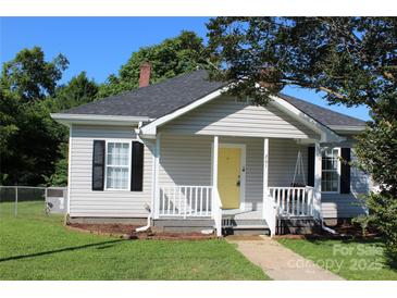 Charming single Gathering home with a freshly manicured lawn and a welcoming yellow front door at 201 Park Ave, Mount Holly, NC 28120