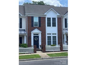 Charming brick townhome featuring a white picket fence and a welcoming dark-blue front door at 4103 Christine Ln # E, Waxhaw, NC 28173