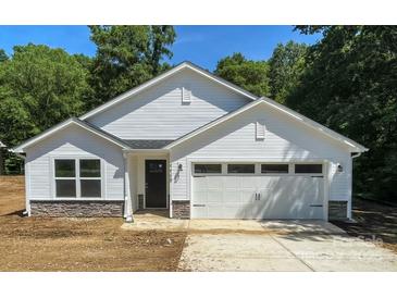 Charming new construction home with stone accents, white siding, an attached garage, and a well-manicured lawn at 4474 Pebblebrook Sw Cir, Concord, NC 28027
