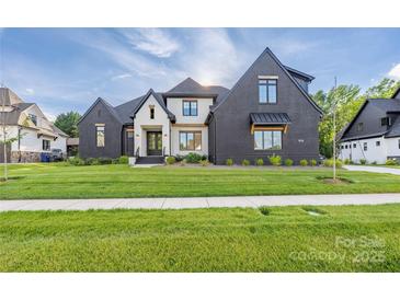 Beautiful home exterior with dark brick, light accents, professionally landscaped yard, and covered windows at 10119 Laurier Ln, Huntersville, NC 28078