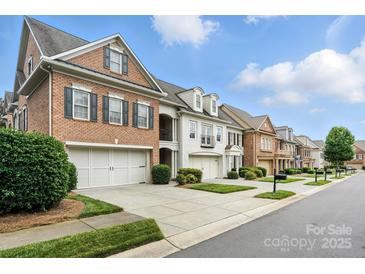 Charming row of townhomes featuring brick and white exteriors, well-maintained landscaping, and attached garages at 11724 Easthampton Cir, Charlotte, NC 28277