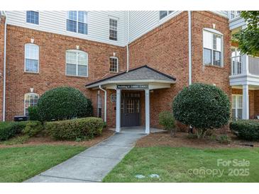 Inviting brick building entrance features well-manicured landscaping and covered entryway with ample natural light at 14624 Via Sorrento Dr # 6206, Charlotte, NC 28277