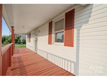 Inviting front porch with red painted wood and white siding, offering a cozy outdoor space at 411 S Central Ave, Landis, NC 28088
