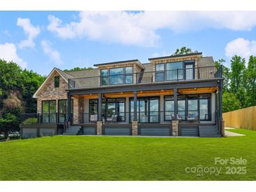 Expansive rear exterior of home with covered porch, stone accents, and well-manicured lawn at 5985 Natoma Rd, Clover, SC 29710