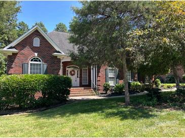 Charming, brick home with a manicured lawn, mature trees, and a welcoming entrance at 2909 Arbor Knl, Concord, NC 28025