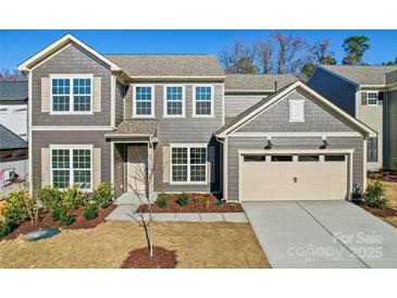 Charming two-story home featuring gray siding, a two-car garage, and manicured landscaping at 1041 Waxhaw Crossing Dr # 058, Waxhaw, NC 28173