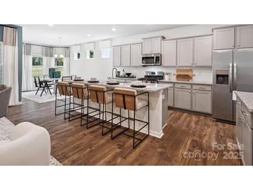 Bright kitchen features grey cabinetry, a granite island with seating, and stainless steel appliances at 1056 Mapletree Ln, Indian Trail, NC 28079