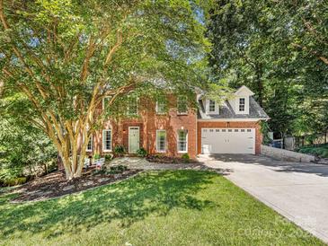 Charming two-story red brick home with attached two-car garage, lush green lawn, and mature shade tree at 11126 Windgate Ct, Tega Cay, SC 29708