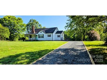 Charming home featuring a well-maintained lawn, gravel driveway and a covered porch at 4501 E Highway 27 Hwy, Iron Station, NC 28080