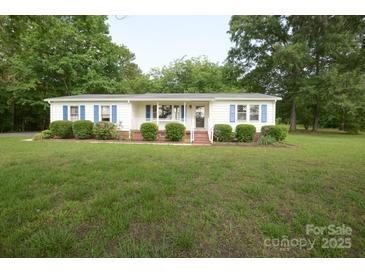Charming ranch-style home with blue shutters, lush lawn and manicured bushes at 7645 Robinson Church Rd, Harrisburg, NC 28075