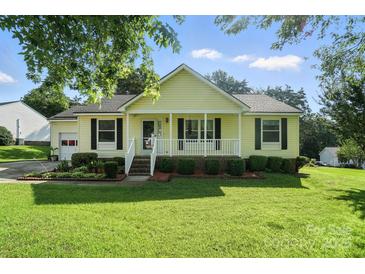 Charming single-story home featuring a welcoming front porch and well-manicured lawn at 8529 Indian Summer Trl, Harrisburg, NC 28075