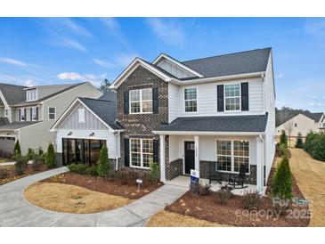 Beautiful two-story home featuring brick and gray siding with a manicured lawn, and rocking chairs on the front porch at 1045 Waxhaw Crossing Dr, Waxhaw, NC 28173