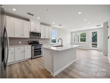 Bright kitchen features white cabinets, stainless steel appliances, gray backsplash, and island with sink at 4455 Reed Creek Dr # 105, Sherrills Ford, NC 28673