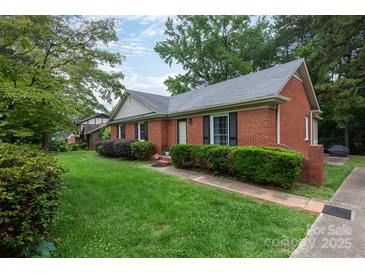 Charming one story brick home with trimmed bushes, green lawn, and mature shade trees in a quiet neighborhood at 5727 Faulconbridge Rd, Charlotte, NC 28227