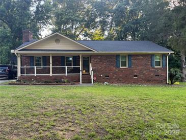 Charming single-story brick home with a cozy front porch and mature trees surrounding the property at 6039 Donna Dr, Charlotte, NC 28213