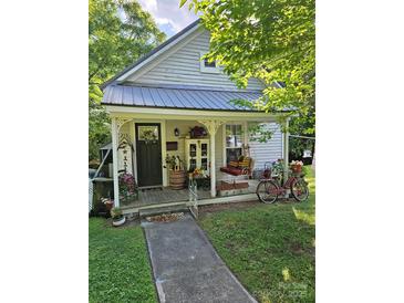 Charming cottage-style home with a quaint front porch decorated with flowers and vintage decor at 215 9Th St, Spencer, NC 28159