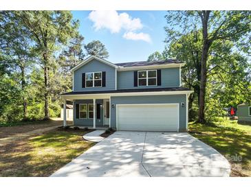 Charming two-story home featuring a covered front porch, attached garage, and well-maintained lawn at 411 Patience Dr, Concord, NC 28025