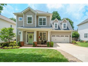 Charming two-story home with inviting front porch, well-manicured lawn and attached two-car garage at 20444 Greenway Heights Dr, Cornelius, NC 28031