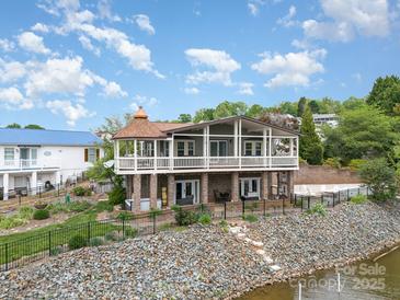 Beautiful waterfront home featuring a spacious porch, well-maintained landscaping, and a charming, copper-roofed turret at 216 Grand View Dr, New London, NC 28127