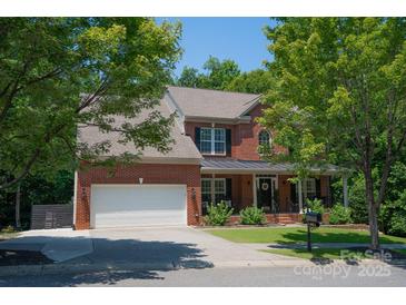 Charming red brick home with a covered front porch, white garage door, and mature trees at 1125 Victoria Blake Ln, Belmont, NC 28012