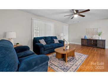 Inviting living room with a comfortable blue sofa, wooden coffee table, and a ceiling fan, creating a cozy atmosphere at 151 Third Creek Rd, Statesville, NC 28677