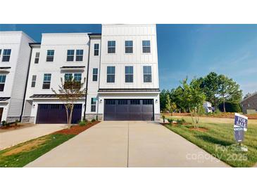 Modern townhouse with a dark garage door, concrete driveway, and well-maintained landscaping at 2143 Barrowcliffe Nw Dr, Concord, NC 28027