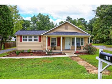 Charming single story home featuring a cozy front porch with rocking chairs and a well-maintained lawn at 218 Blacksnake Rd, Stanley, NC 28164