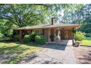 Charming brick home with a covered entryway, mature landscaping, and a long driveway at 5329 E Highway 27 Hwy, Iron Station, NC 28080