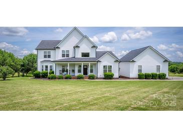 Charming two-story home with a covered front porch, manicured lawn, and lush landscaping at 594 Patterson Farm Rd, Mooresville, NC 28115