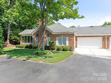 Charming brick home with a well-maintained lawn, mature tree, and an attached two-car garage at 8465 Olde Troon Dr, Charlotte, NC 28277